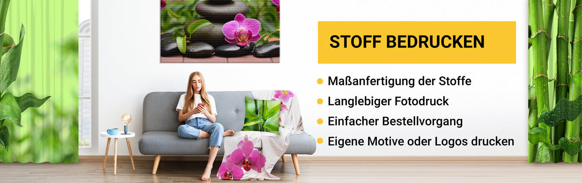 Frau auf einer Couch mit bedrucktem Kissen, bedruckter Decke, bedruckter Leinwand and der Wand und bedruckten Vorhängen am Fenster