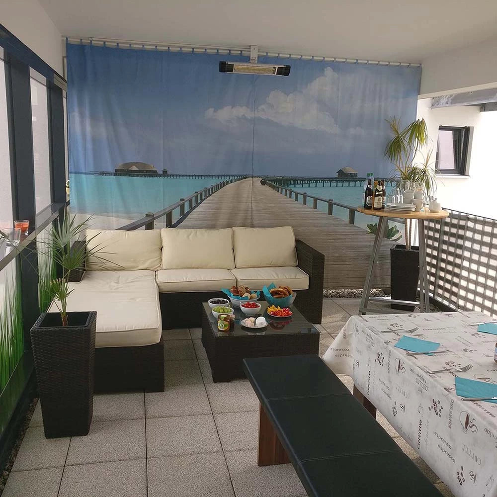 Auf einem großen Balkon dient ein Vorhang mit Meeresmotiv and der Wand als Dekoration