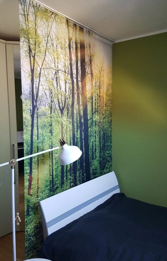 ein mit Waldmotiv bedruckter Schiebevorhang dient als Raumteiler im Schlafzimmer