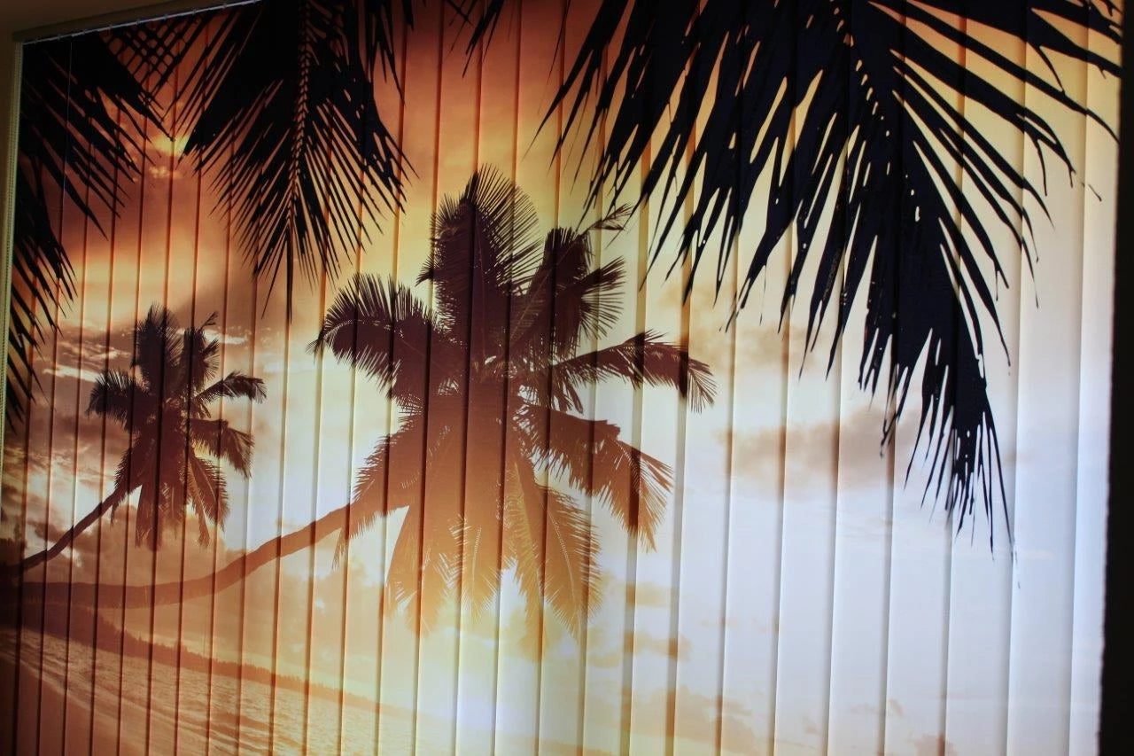 Frontansicht von einem großen bedruckten Foto-Lamellenvorhang an einer großen Fensterfront bedruckt mit Palmen bei Sonnenuntergang am Meer