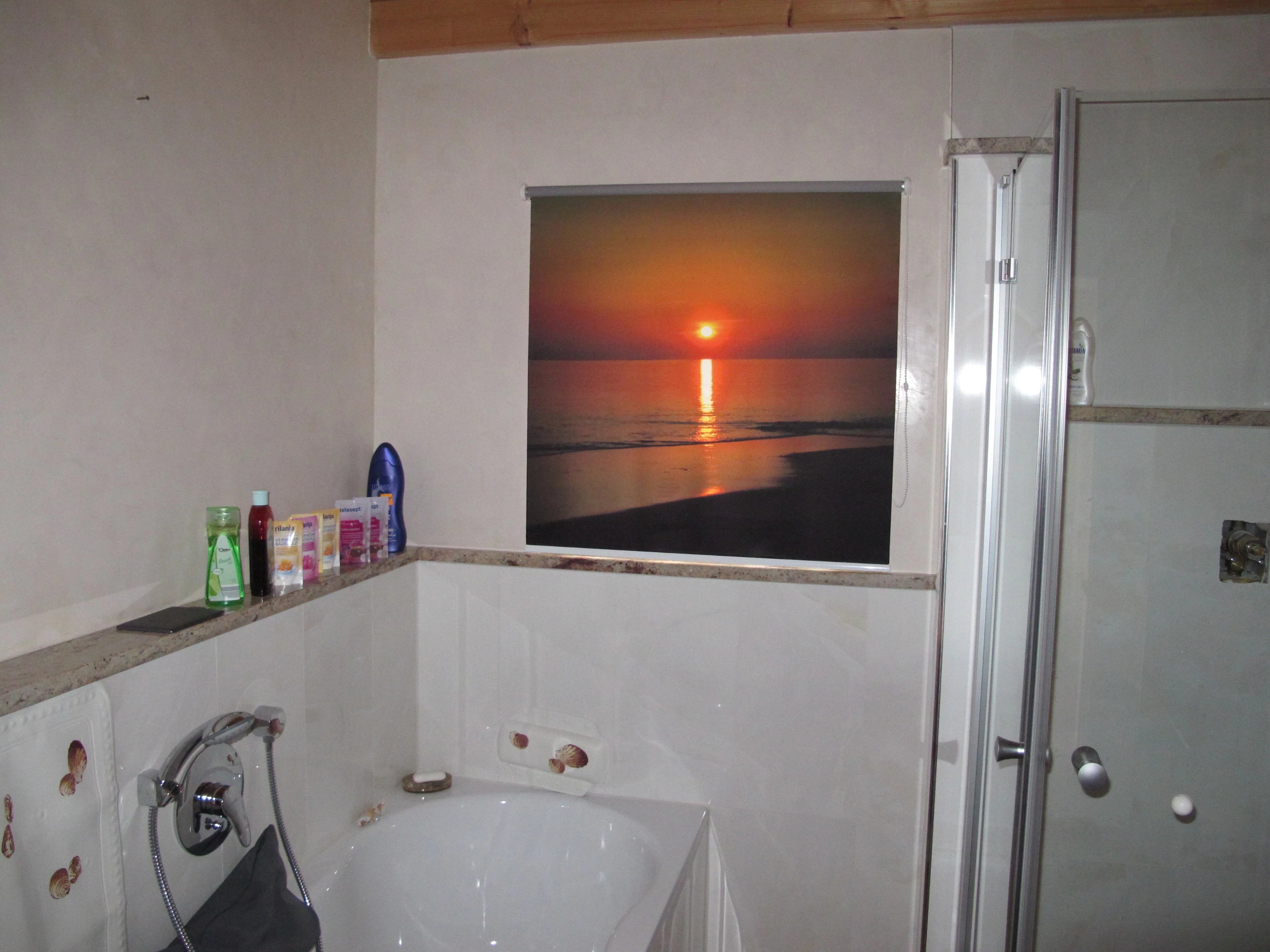 bedrucktes Fotorollo im Badezimmer am Fenster mit Bild vom Sonnenuntergang am Meer