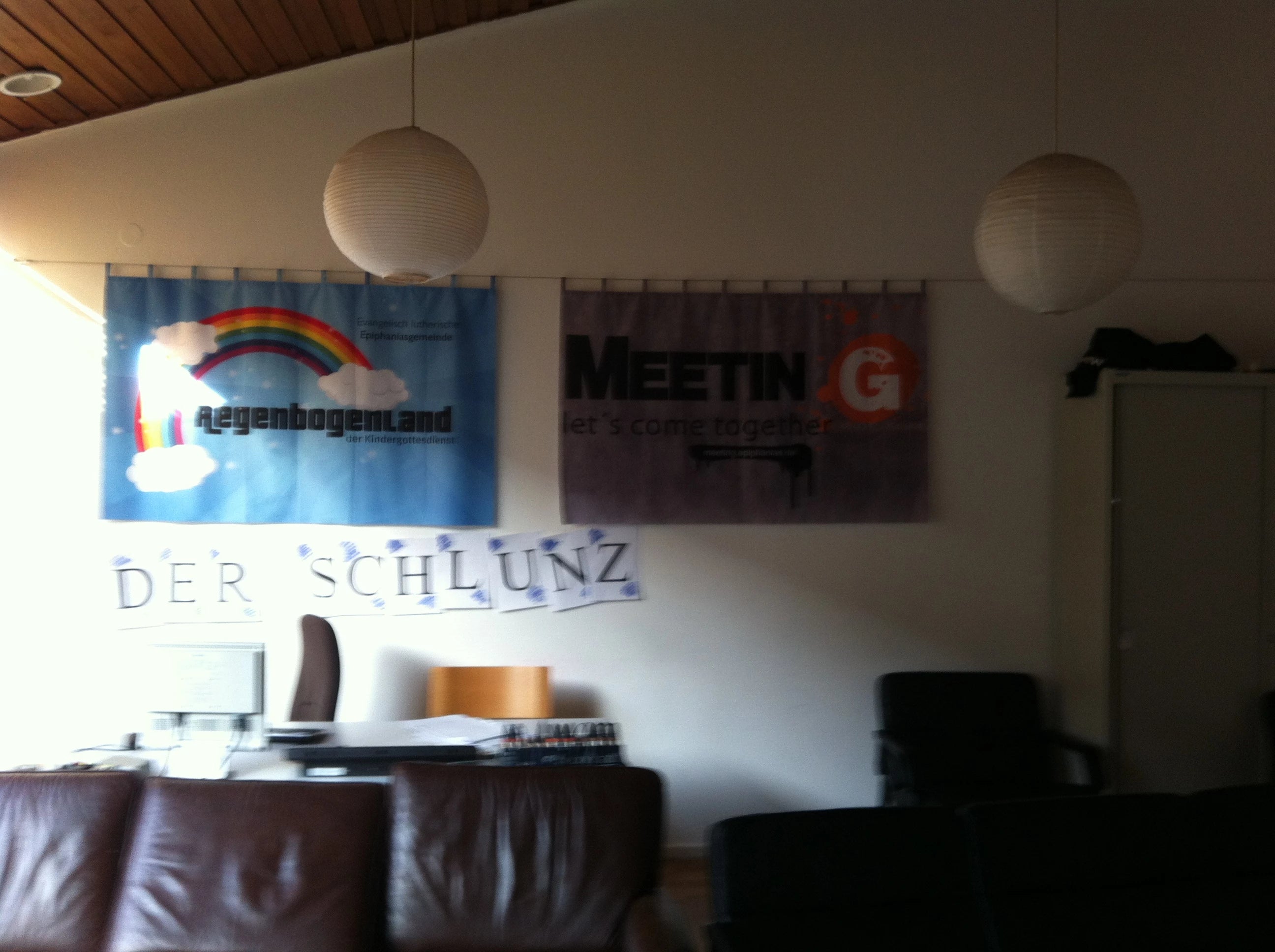 zwei bedruckte Vorhänge als Wandbehang mit Regenbogen und mit Logo als Motiv im Büro einer Kirchengemeinde