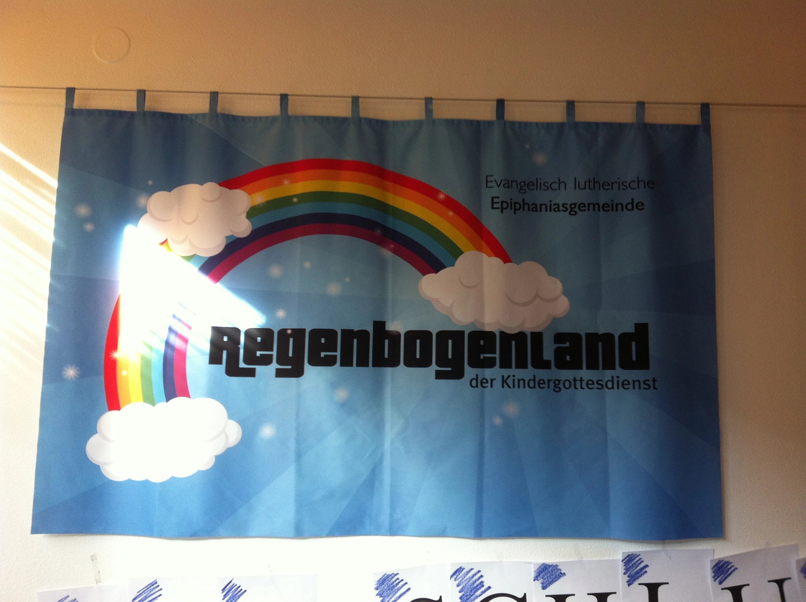 Foto-Vorhang bedruckt mit Regenbogen als Werbung für den Kindergottesdienst einer Kirchengemeinde als Wandbehang