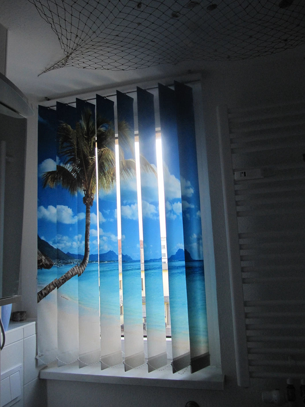 Bild einer Palme am Strand gedruckt auf einem Foto-Lamellenvorhang im maritim eingerichteten Badezimmer am Fenster 