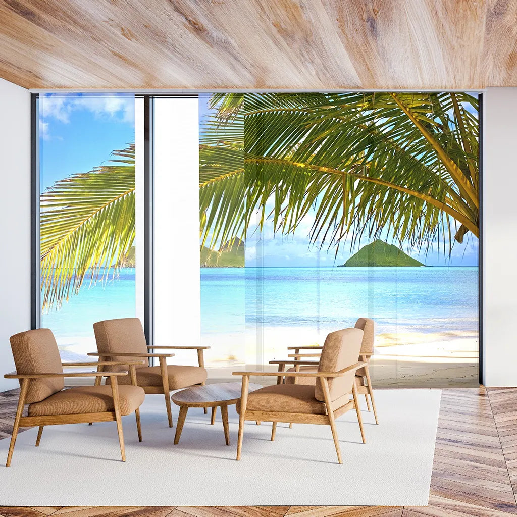 Schiebegardinen mit Palmen und Meeresmotiv am Fenster hinter einer Sitzgruppe