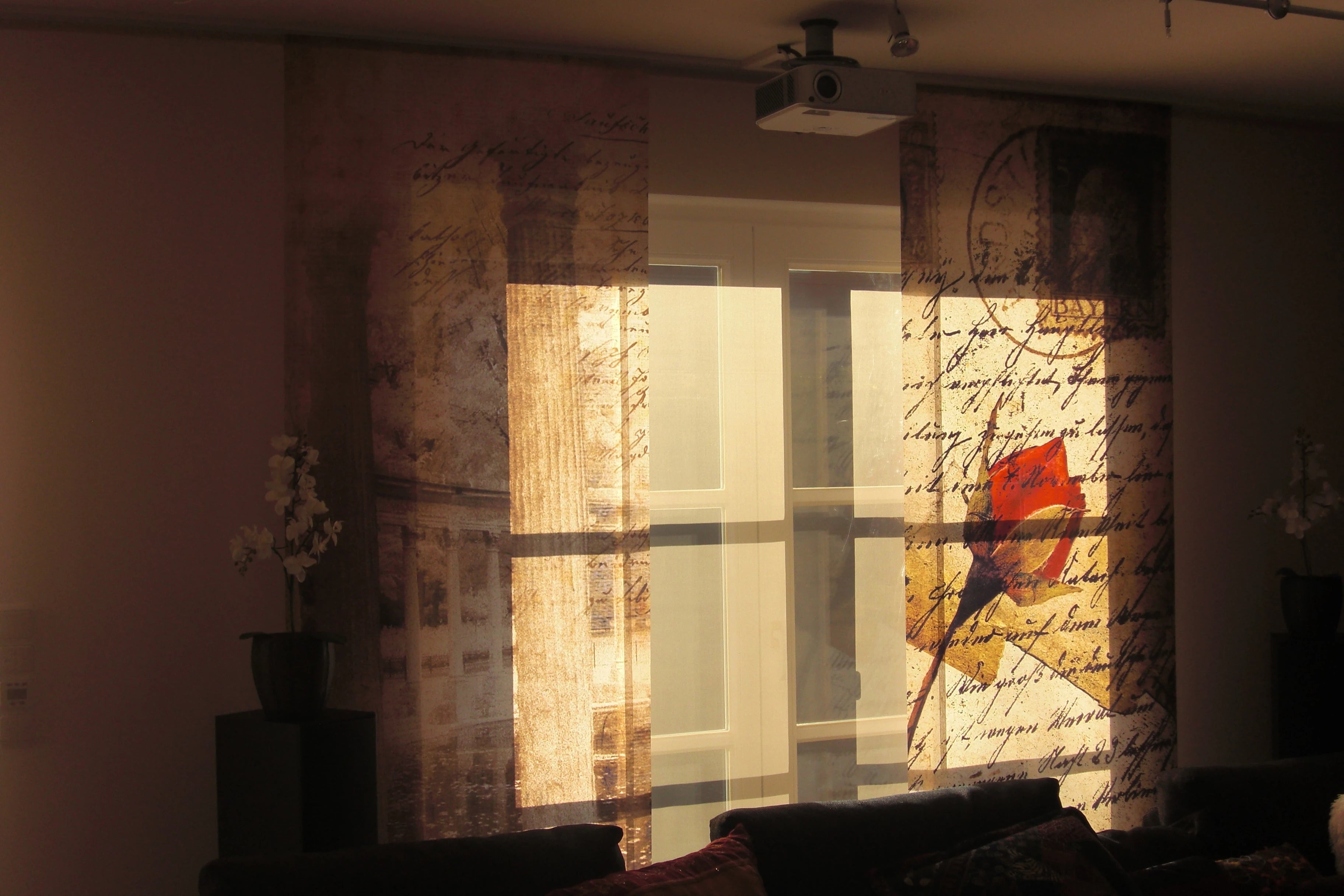 Wohnzimmer mit Rerrassenfenster. Daran links und rechts eine Schiebegardine bedruckt mit einem Rosenmotiv in sepia