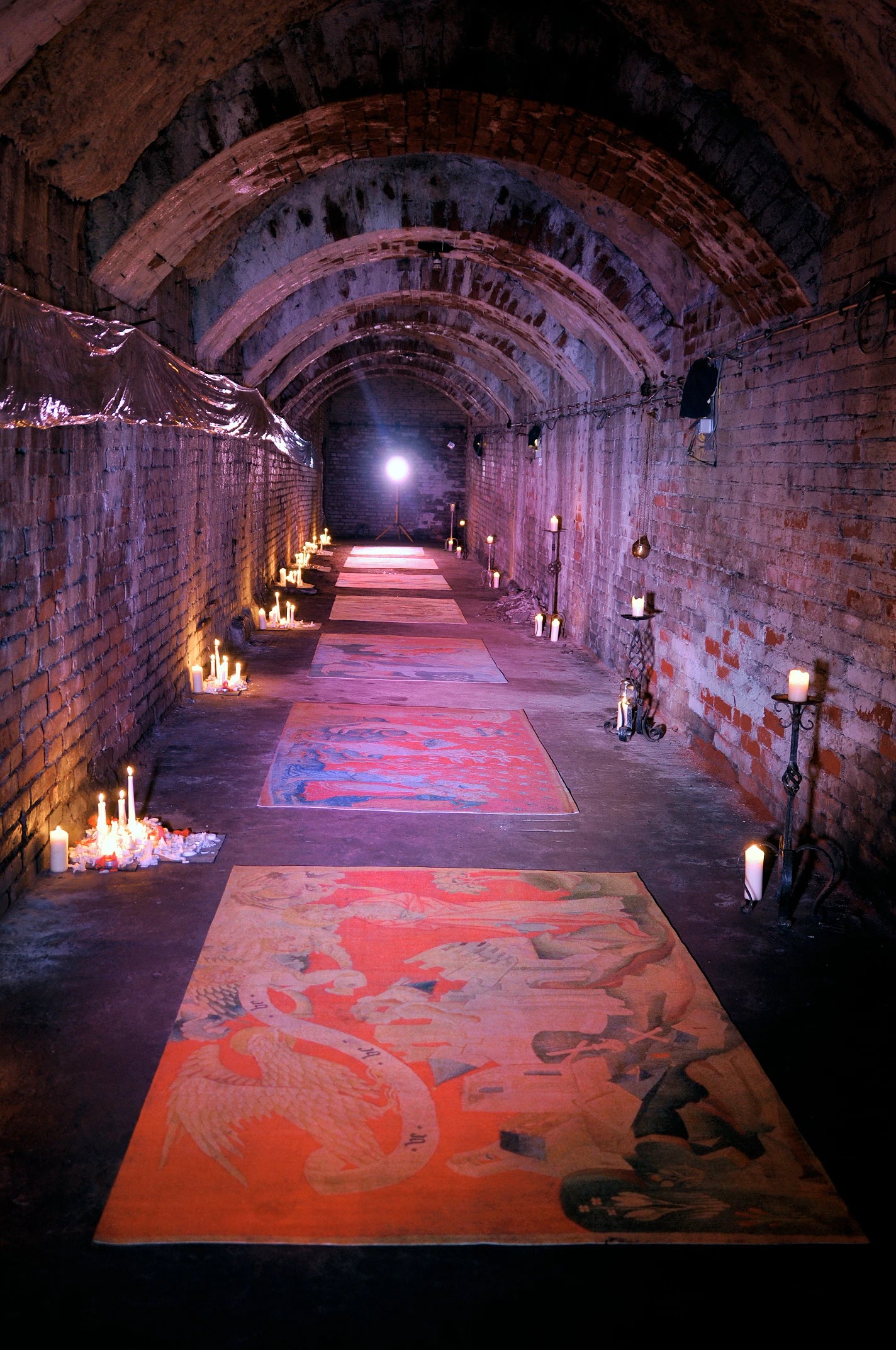 Katakomben mit Kerzen im Gang an den Seiten und ausgelegten Teppichen bedruckt mit altertümlichen Motiven