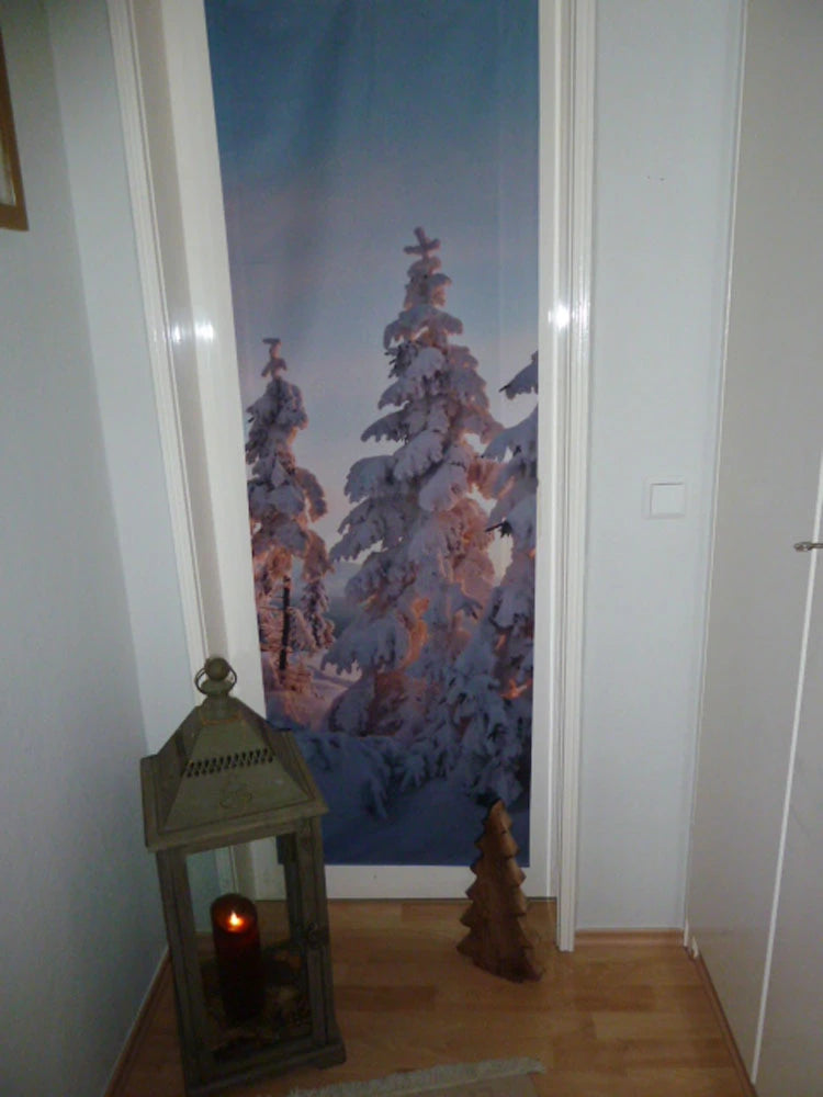 Eine Glastür wird durch einen mit Motiv bedruckten Vorhang mit dem Bild einem winterlichen Wald im Sonnenuntergang bedeckt